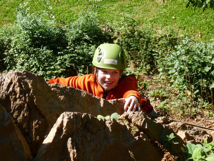 Kind klettert einen Felsen hoch